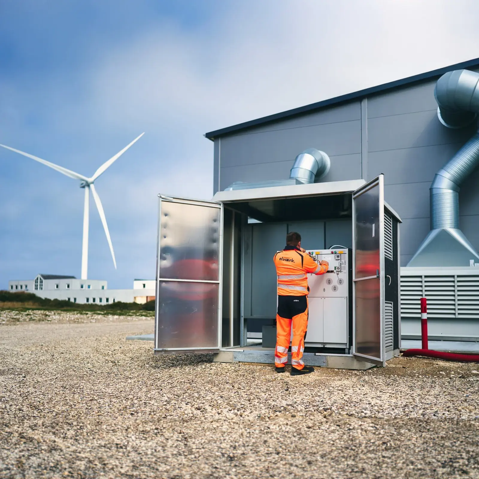 En mand der står ved en eltavle ude ved vindmøller.